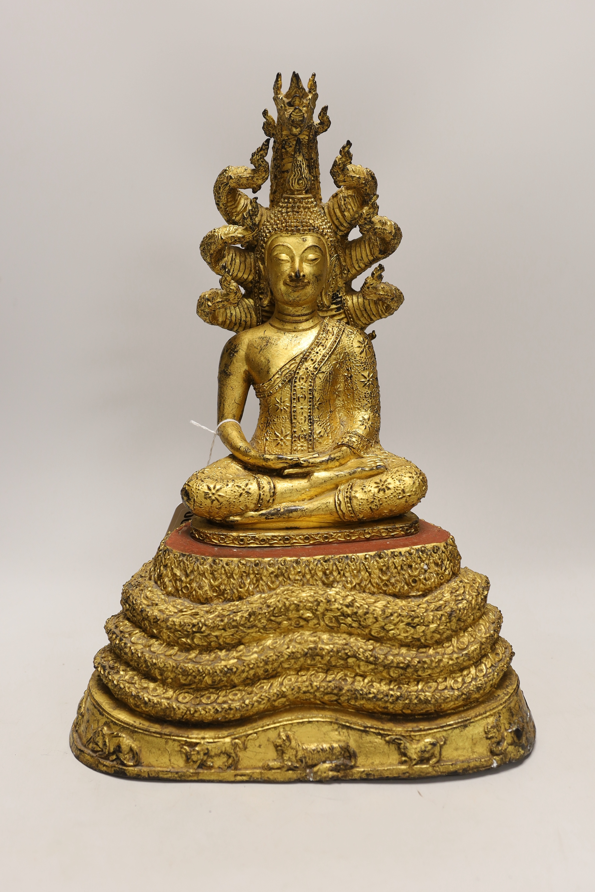 A large Thai gilt bronze seated figure of Buddha on a naga throne, 43cm high